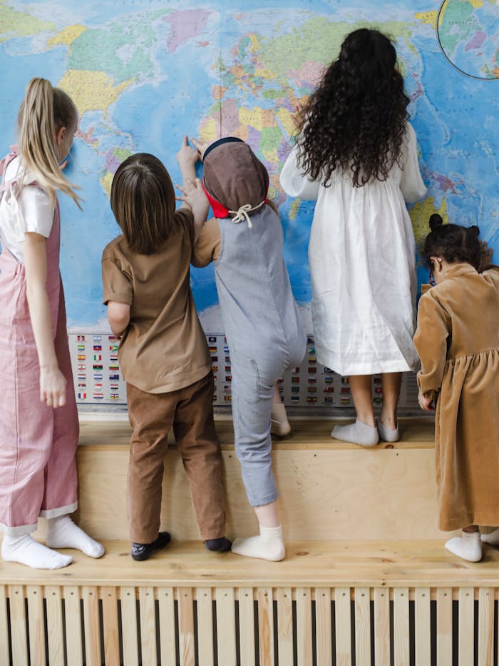 Five children studying a world map indoors, fostering curiosity and learning.